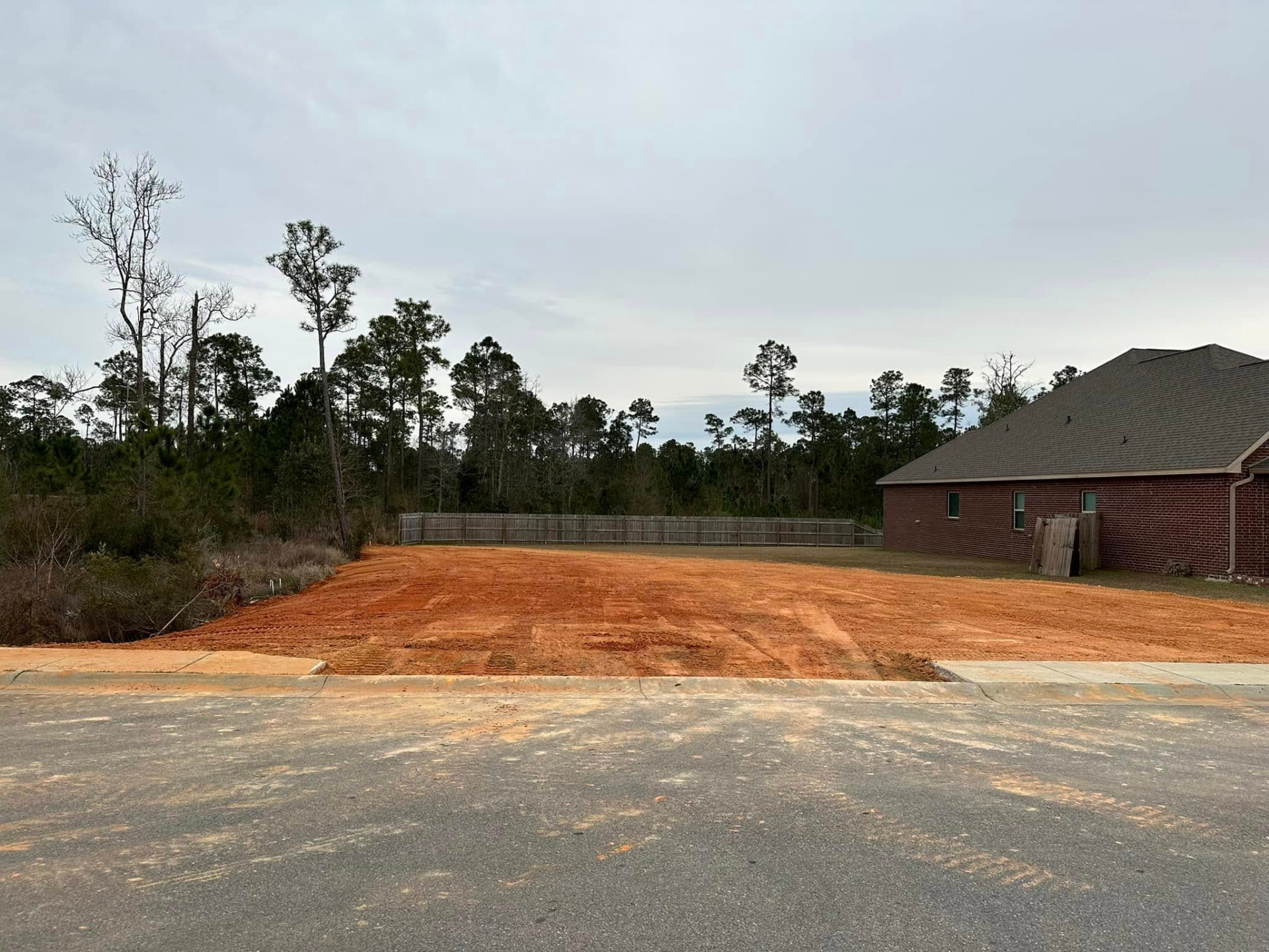 Graded dirt pad prepped beside a brick home