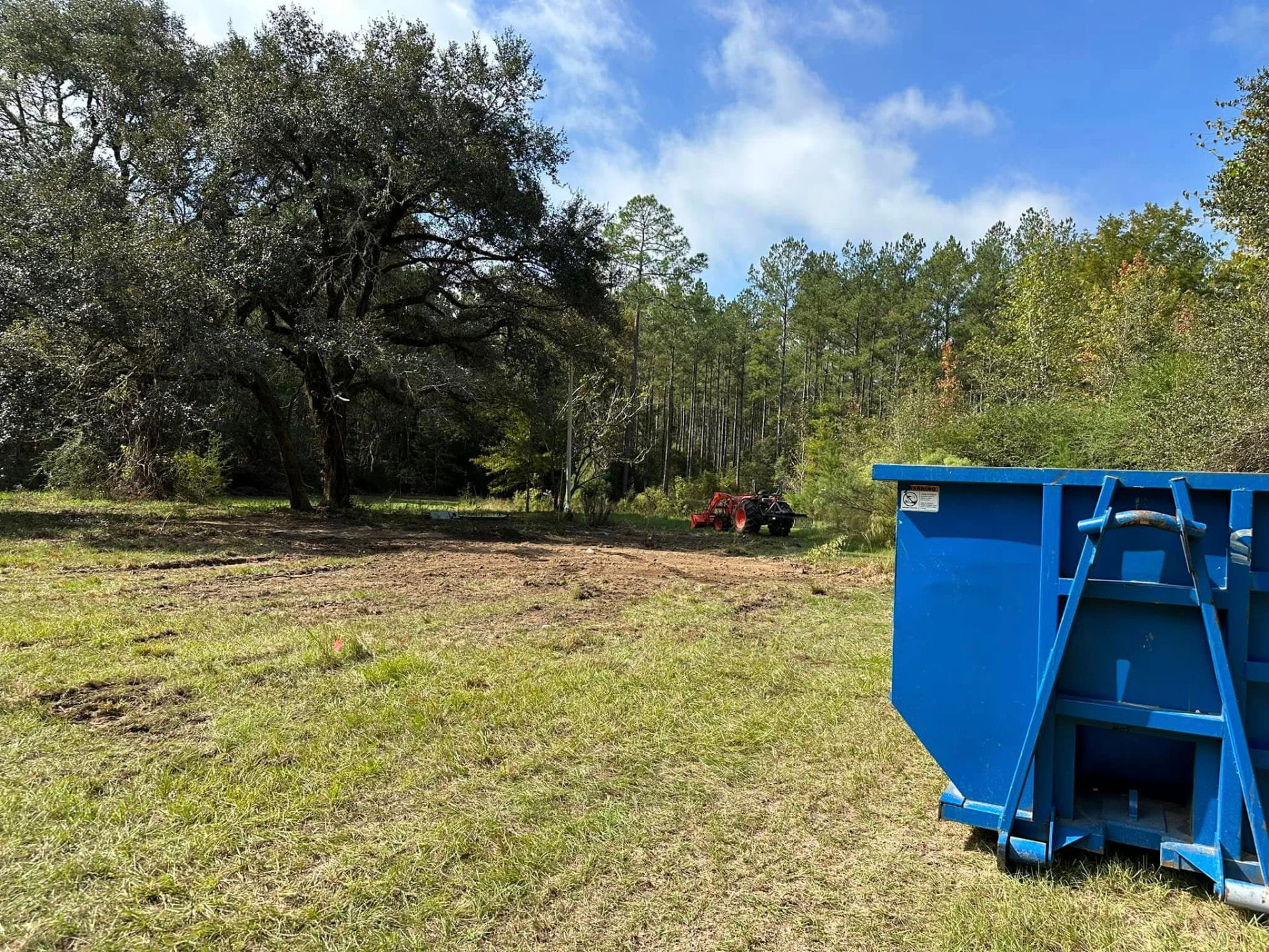 Cleared lot with dumpster after mobile home demolition