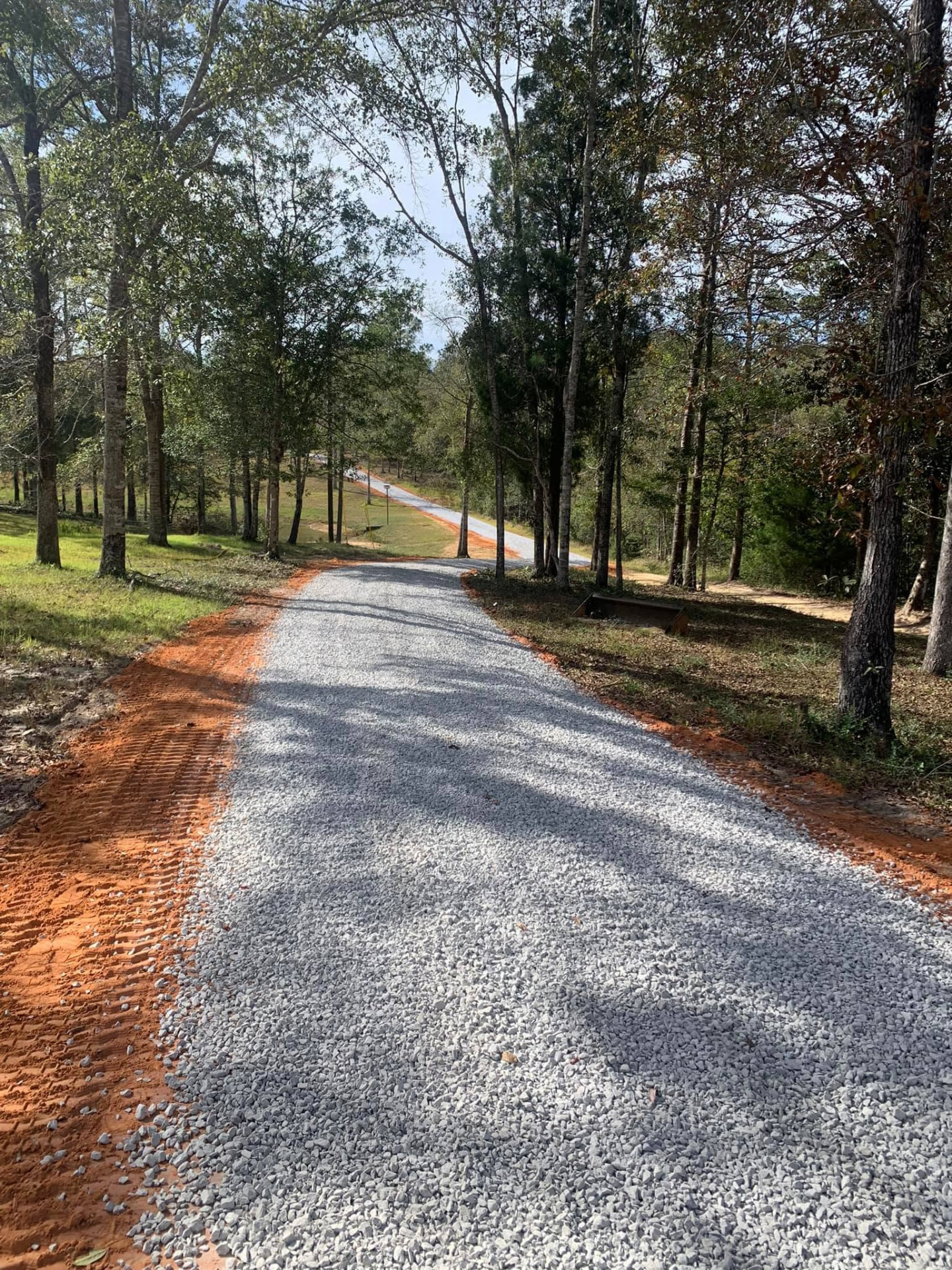 Long gravel driveway installed through a wooded property